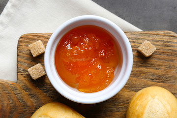 Tasty jam in the jar and bowl, crackers and fresh buns close-up