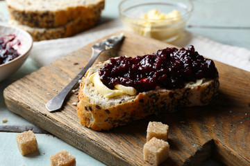 Tasty jam in the bowl, butter, fresh bread and crackers on blue wooden background