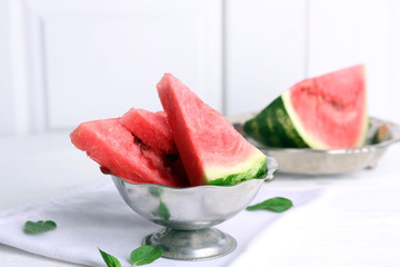 Sliced watermelon in metal bowl on white table