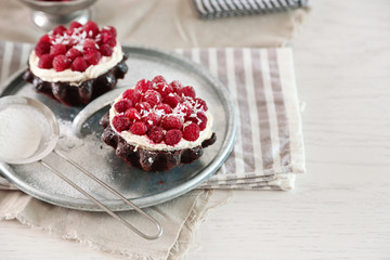 Sweet cakes with raspberries on light wooden background