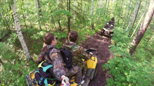 Two guys on quad ride through the forest