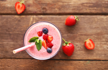 Fresh strawberry yogurt with berries around on wooden background