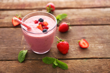 Fresh strawberry yogurt with berries around on wooden background
