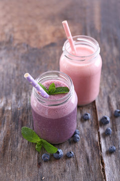 Healthy strawberry yogurt with mint and berries around on wooden background
