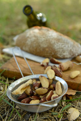 Picnic composition of red wine, delicious cheese, nuts and bread on wooden board, close up