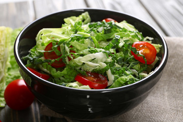 Savoy cabbage and tomato salad served in bowl on wooden table