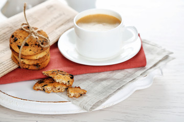 Cup of coffee and pile of tasty cookies with chocolate crumbs on white wooden table