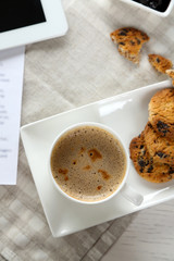 Cup of coffee and tasty cookies with chocolate crumbs on grey checkered napkin, close up