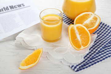 Newspaper with oranges and juice on blue checkered napkin
