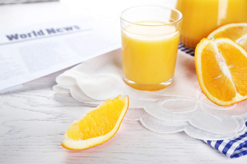 Newspaper with oranges and juice on blue checkered napkin