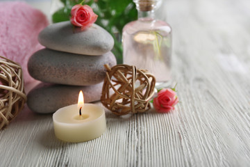 Plakat Composition of flowers, candles and stones on white wooden background, in spa salon