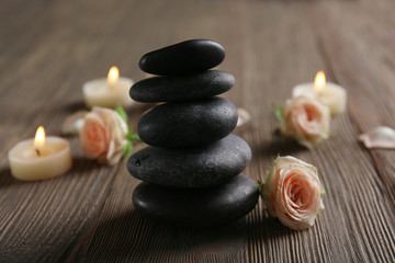 Composition of flowers, candles and stones on brown wooden background, in spa salon