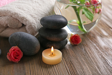 Spa composition of candles, flowers and stones on brown wooden background