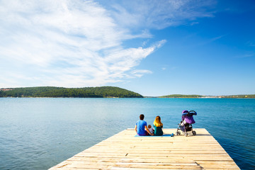 Family with Little Baby Sitting on Pier near the Sea