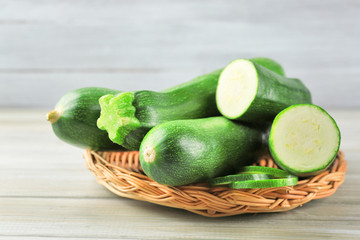 Fresh zucchini on wicker mat on wooden background