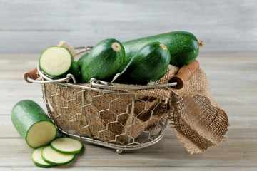 Fresh zucchini in wicker basket on wooden background