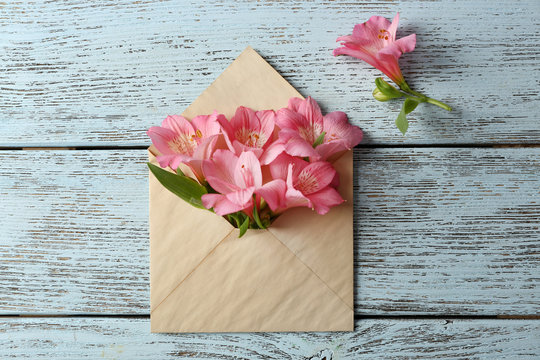 Pink alstroemeria in envelope on wooden background