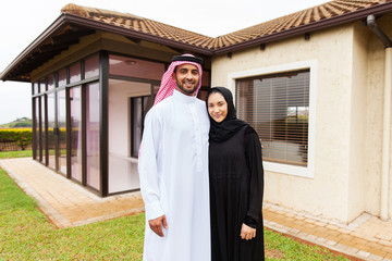 young muslim couple standing in front of their house