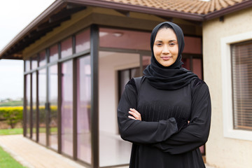 middle eastern woman standing in front of her house