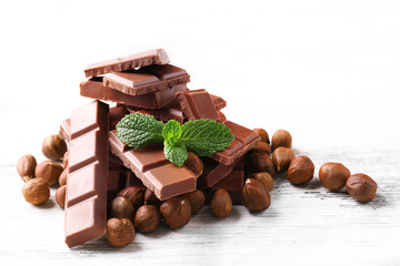 Chocolate pieces with nuts on color wooden background