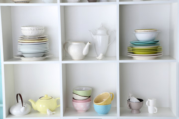 Different clean dishes on wooden shelves