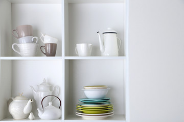 Different clean dishes on wooden shelves