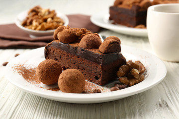 Chocolate balls and a piece of cake with walnut on the table, close-up