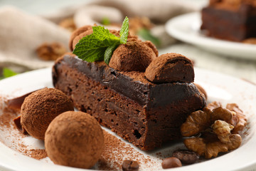 Chocolate balls, a piece of cake with walnut and mint on the table, close-up