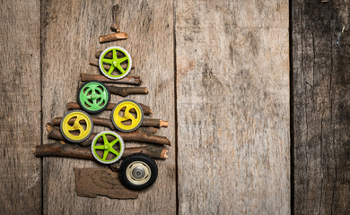 Christmass tree made of twigs and colorfull wheels on wooden background with copy space