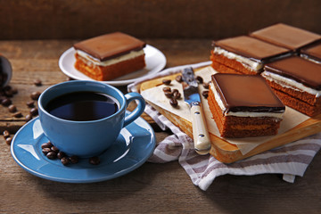 Delicious chocolate brownies and coffee mug on wooden background