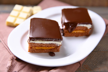 Delicious chocolate brownies on plate, on wooden background