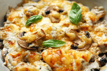 Roasted mushrooms, chicken and cheese gratin in pan, on wooden background