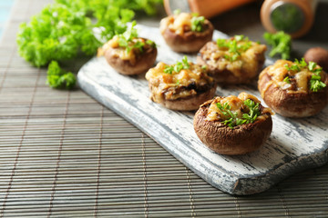Stuffed mushrooms on wooden board, on table background