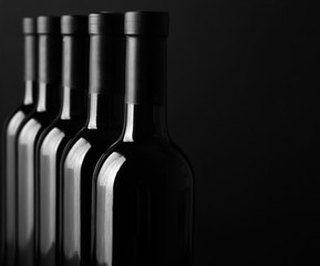 Wine bottles in a row on black background, close up