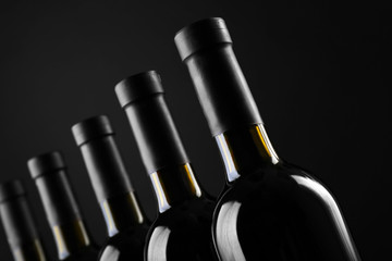 Wine bottles in a row on black  background, close up
