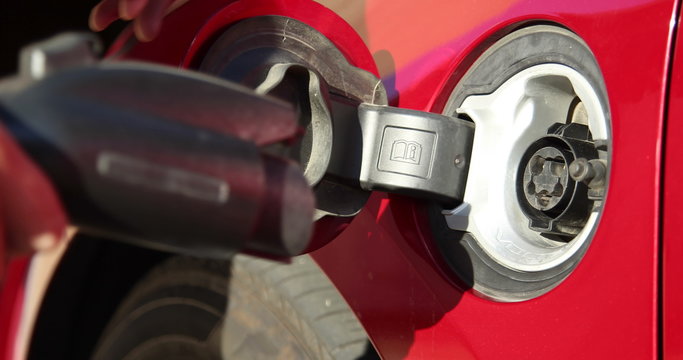 Close up of an Electric Vehicle's charge port as it's opened and plugged in.