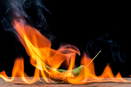 green pepper with flame on black background