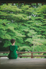 Fototapeta premium Woman sitting in front of a Japanese garden, Kyoto, Japan