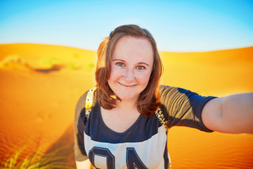 Happy tourist taking selfie with sand dunes in Sahara