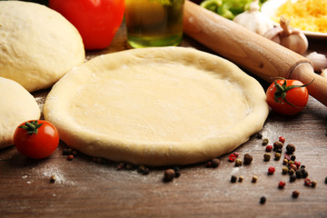 Dough basis and ingredients for pizza, on the table