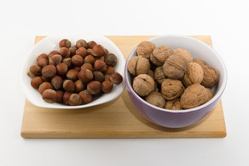 platefuls of different nuts stand on a plate on a white backgrou