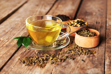 Glass cup of tea with mint leaves and herbs on wooden background