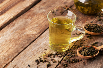 Glass cup of tea and teapot on wooden background