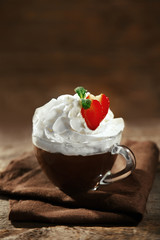 Hot chocolate with whipped cream in mug  on wooden background