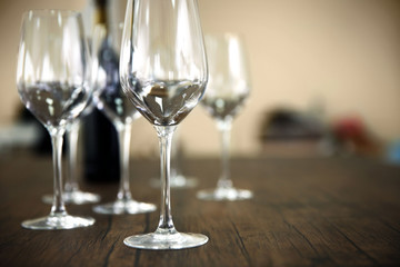 Empty wine glasses with bottle on wooden table against blurred background