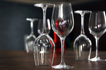 Construction of empty wine glasses and bottle on wooden table against blurred background