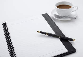 Notebook with a pen and a cup of coffee