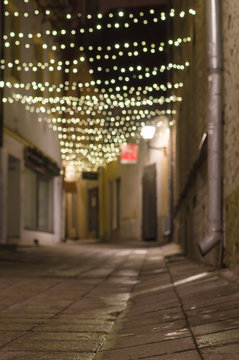 Blurred image of narrow city street decorated with illuminated festoon