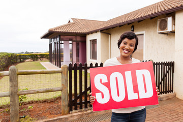 african woman holding sold sign in front of house