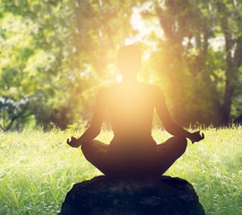 Woman is meditating in sunset of forest